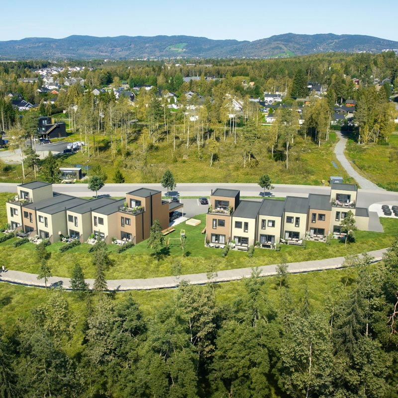 3D-visualisering i fugleperspektiv av Havrely boligtun, med moderne rekkehus og rekke eneboliger omkranset av grønn skog, turveier og boligområde.